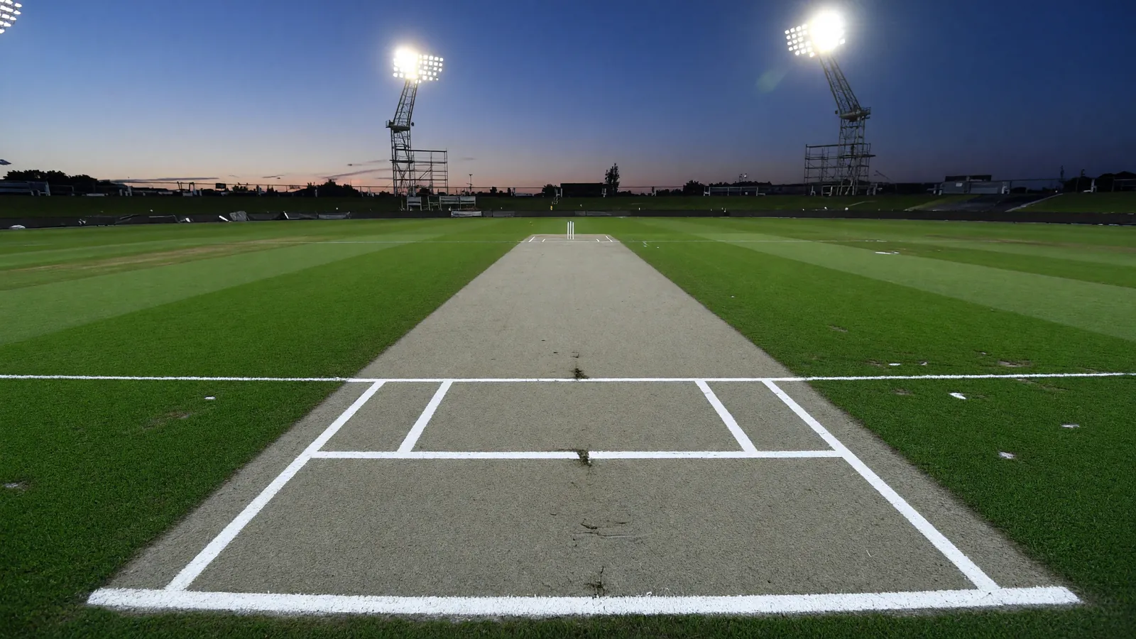 A freshly painted cricket crease at a floodlit evening venue